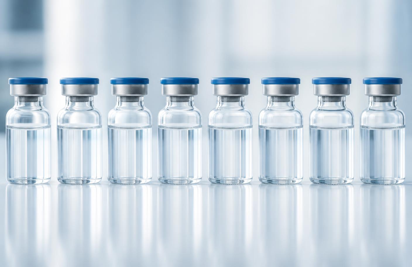 Row of sealed glass laboratory vials on a reflective white surface